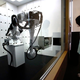A robot arm moves a box containing a suitcase.
